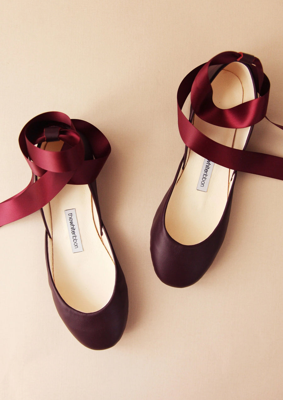 bordeaux leather ballet flats with matching satin ankle straps on light background in front view