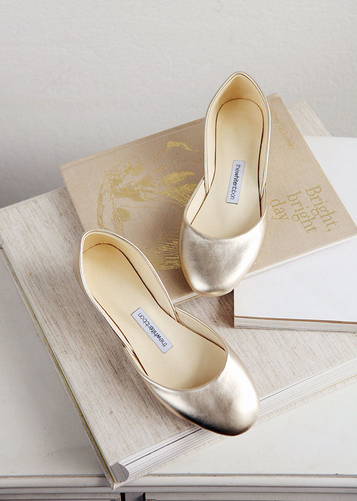Gold leather ballet flats, placed on top of books. 