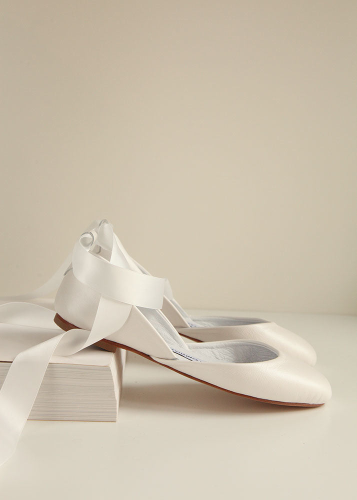 Pearl ivory bridal leather ballet flats with satin ribbons, shown in a sideview on neutral background. 