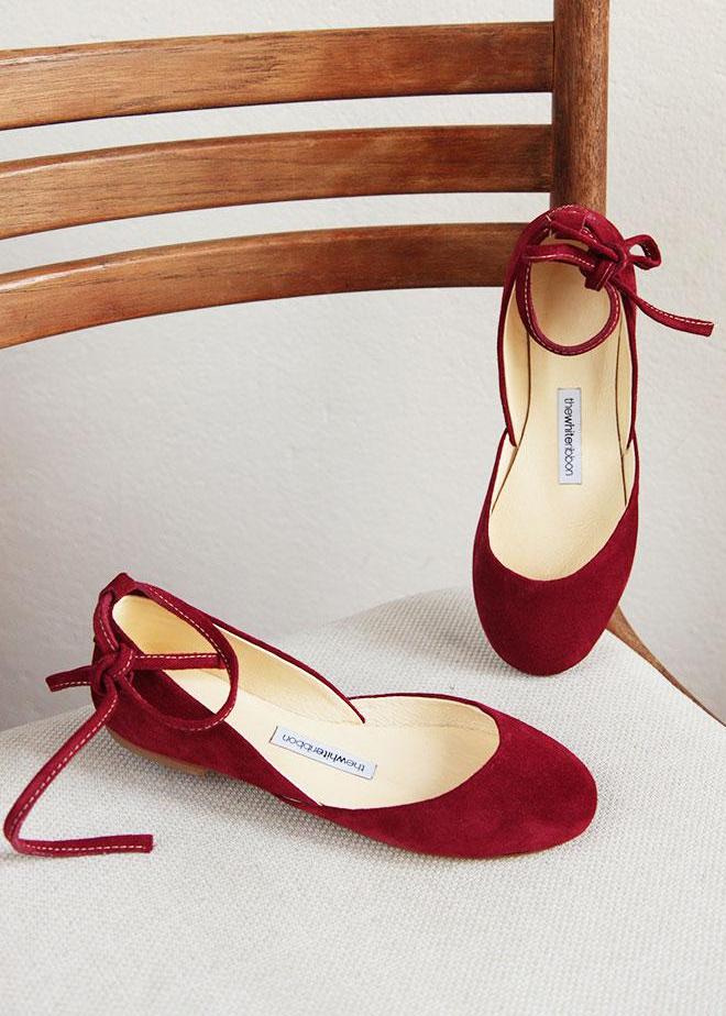 Cherry red suede ballet flats with long leather ankle ribbons in front view