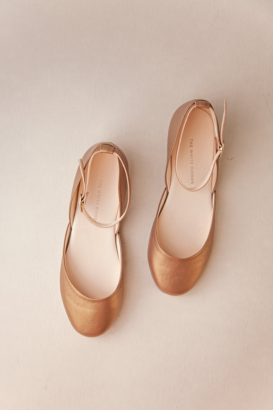 Pair of beige shoes on a light beige background