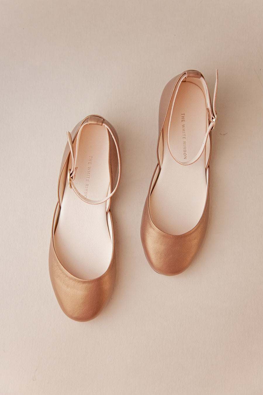 Pair of gold ballet flats on a beige background