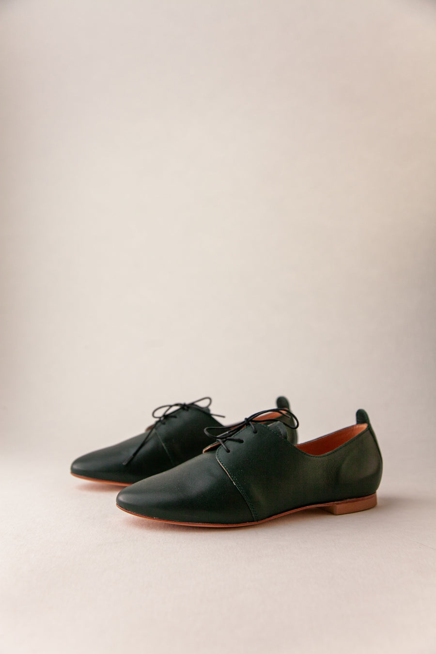 Pair of green leather shoes on a beige background