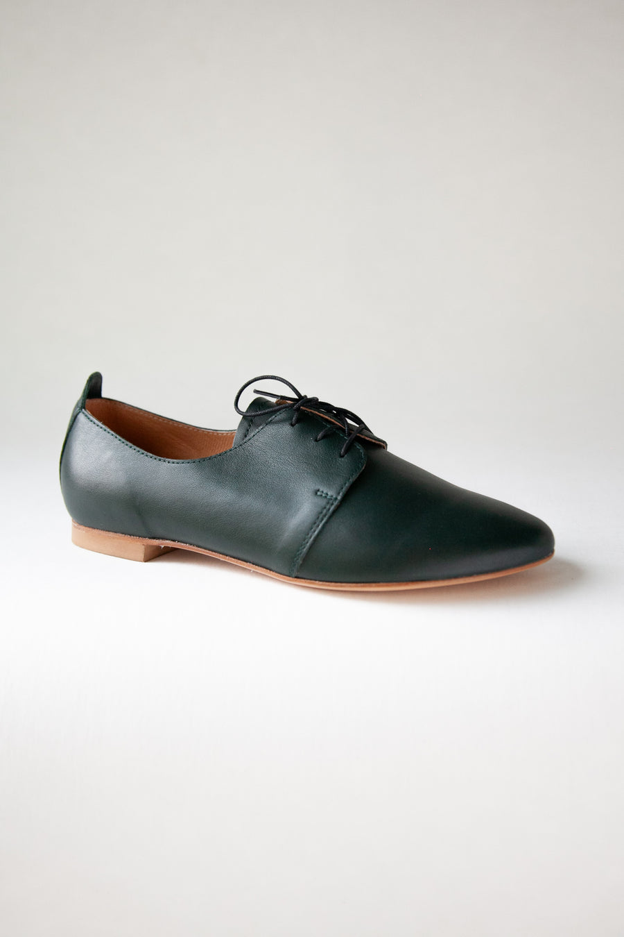 DArk green laced shoes against white background