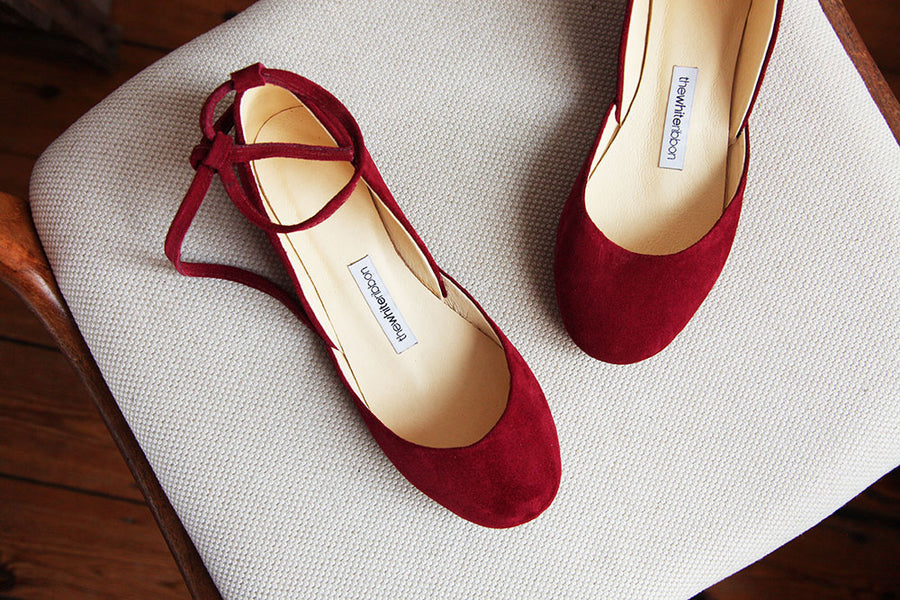 Cherry red leather ballet flats with leather ankle ribbons in close up