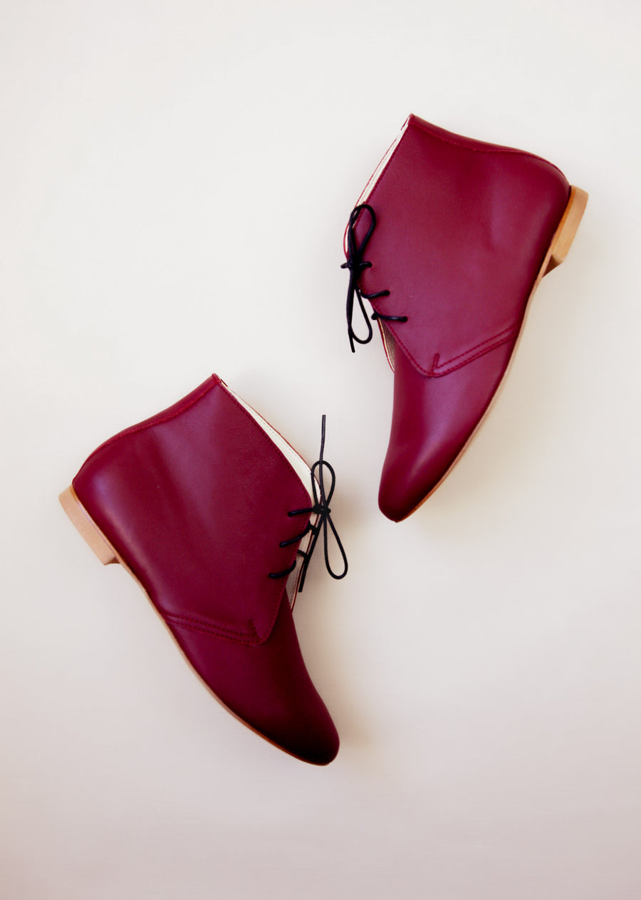 Bordeaux leather boots from top view on beige background. 