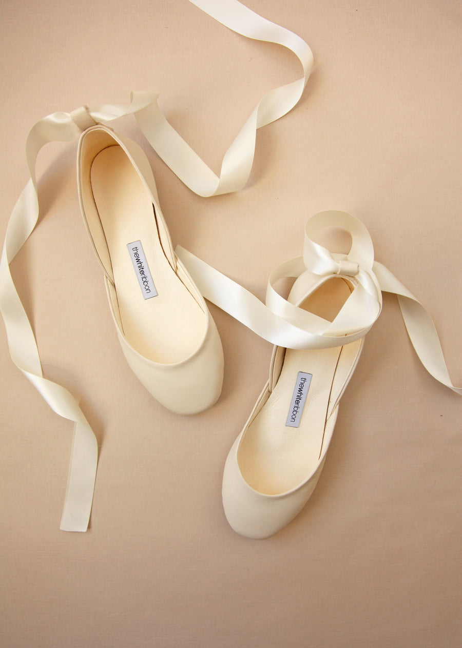 vanilla ivory leather ballerinas with satin ankle straps from top on pastel background