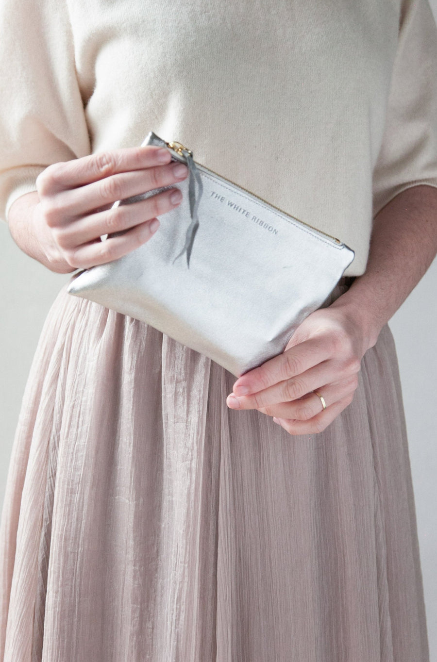 Model in long skirt holding silver leather purse