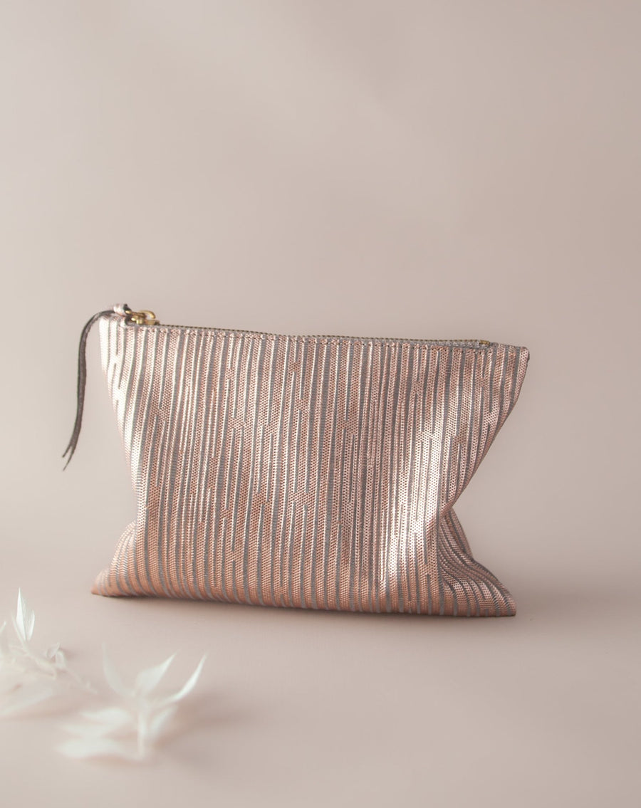 Rose gold clutch with stripes on beige background