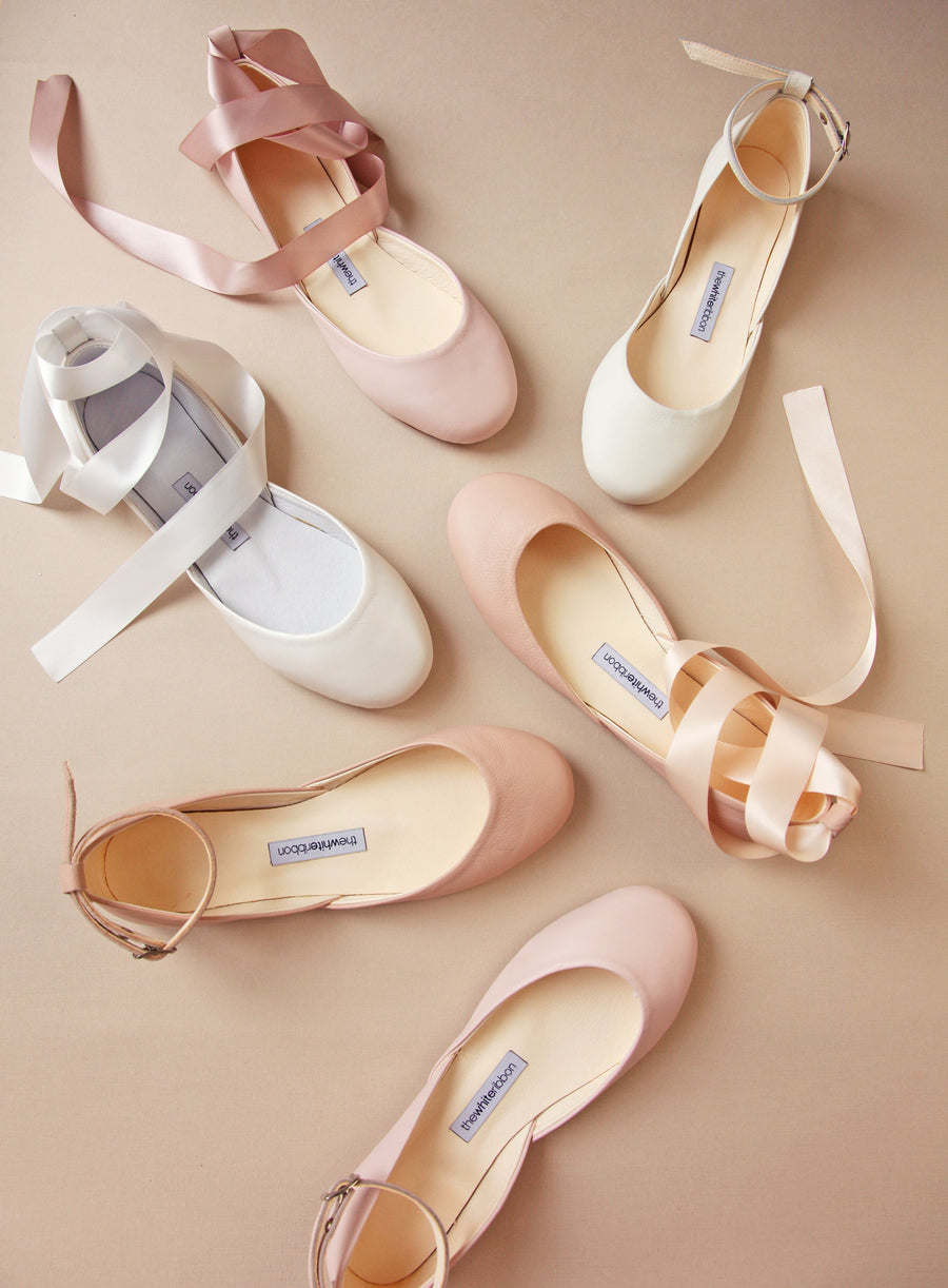 Selection of 6 bridal shoes in blush, white and ivory colours with either satin ribbons or leather ankle straps. Shown from a top view. 