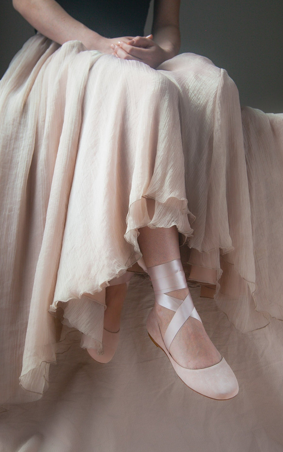 woman sitting with long skirt and blush lace up ballet flats