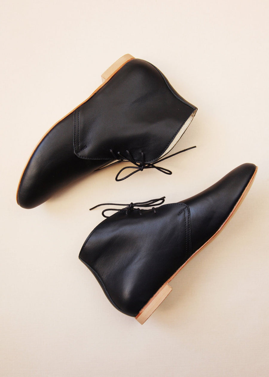 smooth black leather ankle boots shown from the side on cream background 