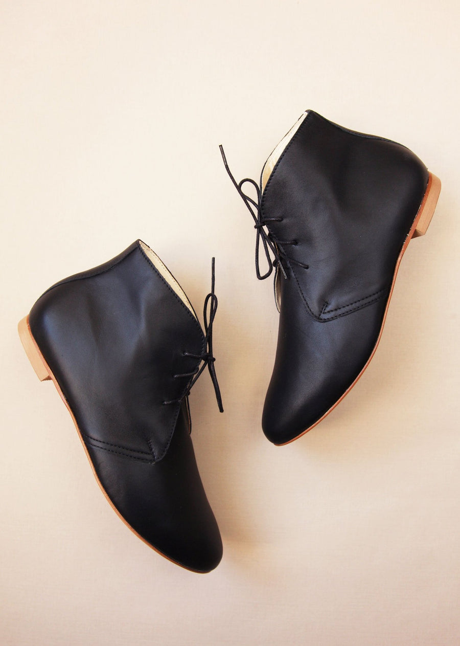 pair of black leather ankle boots side view with cream background
