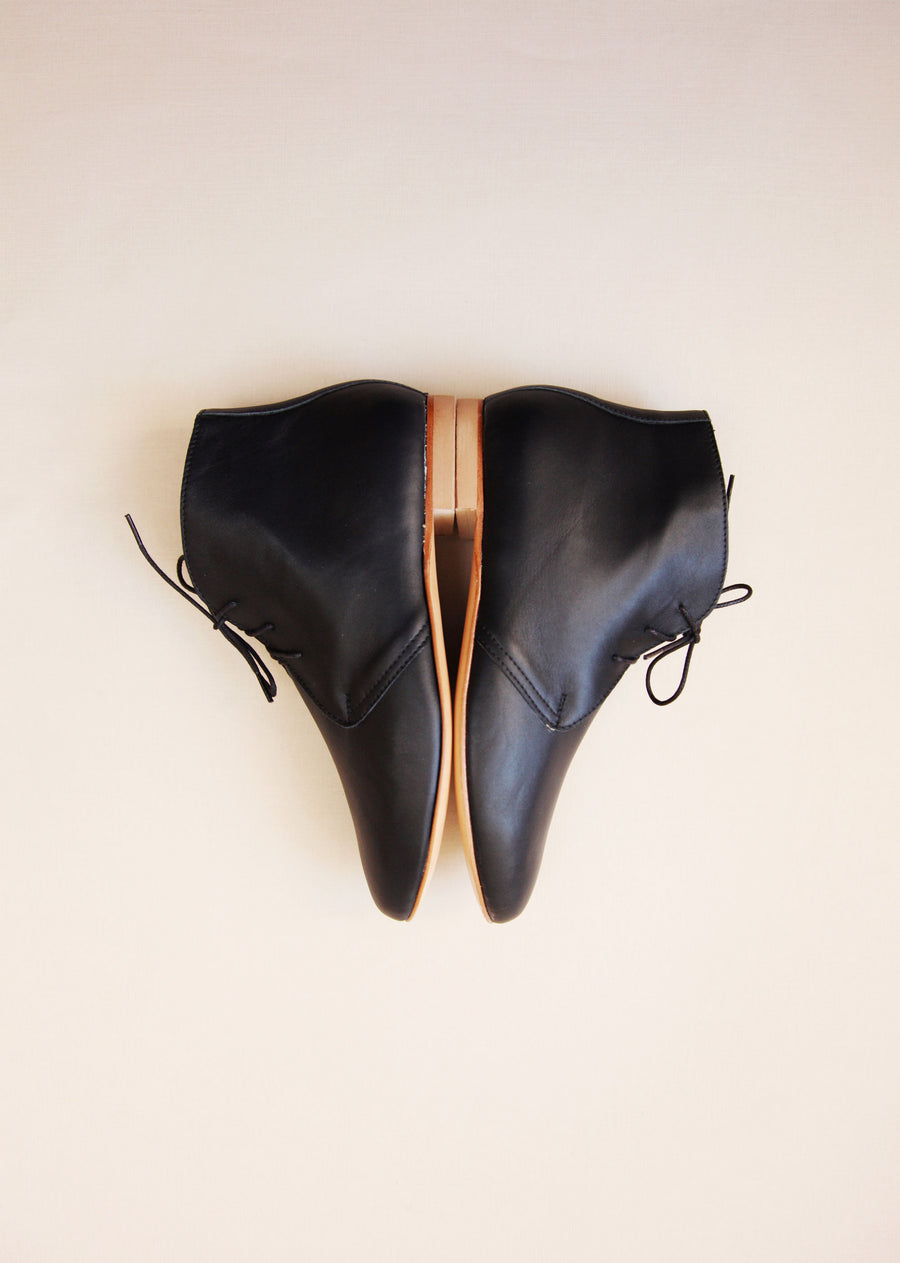 mirrored side shot of black leather booths with shoelaces on light bacground