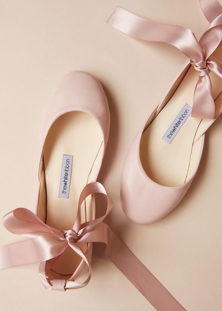 top view of a pair of blush leather ballerinas with blush satin ribbons