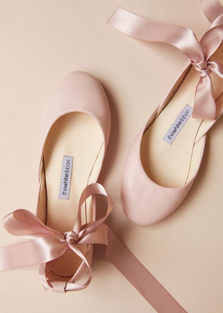 top view of a pair of blush leather ballerinas with blush satin ribbons
